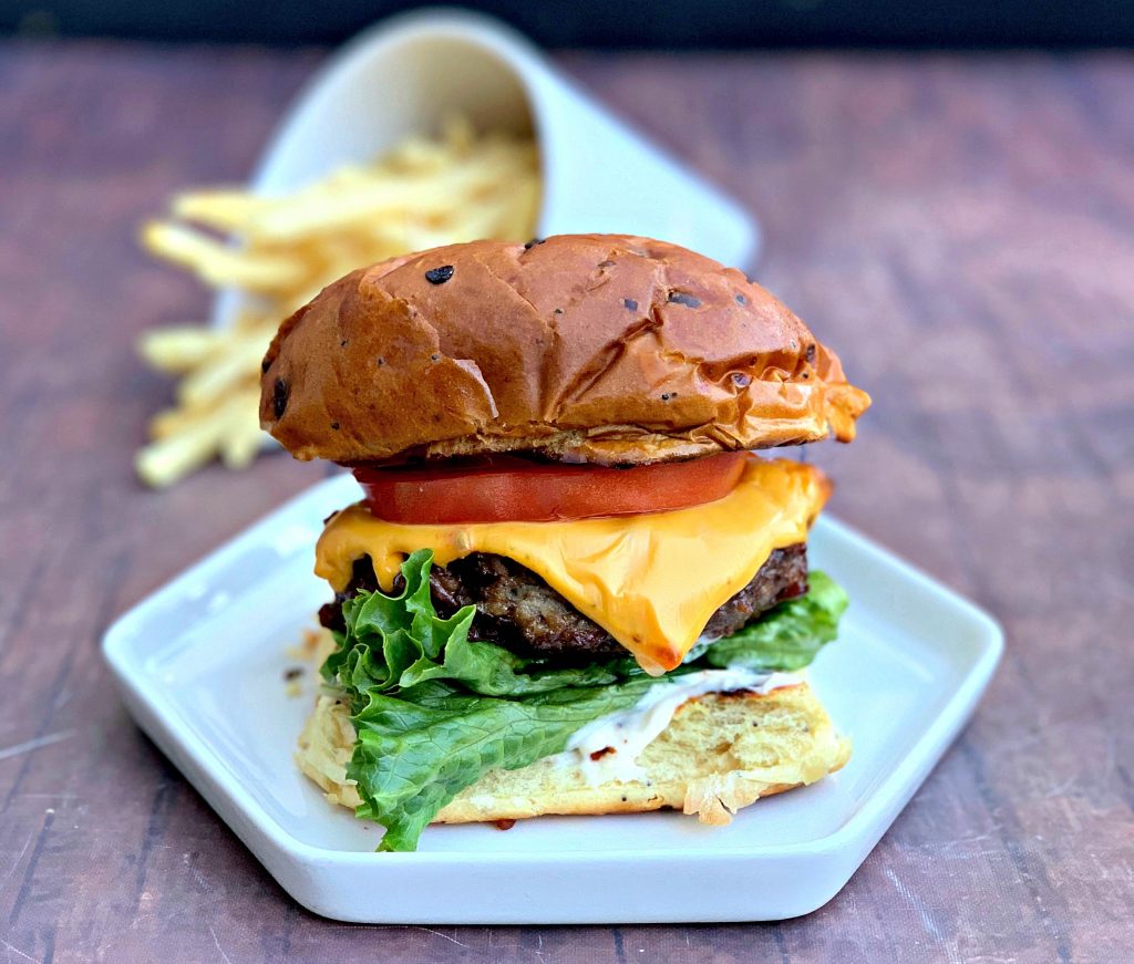 juicy air fryer cheeseburgers on a bun and white plate with fries