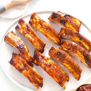 air fryer ribs on a white plate with bbq sauce