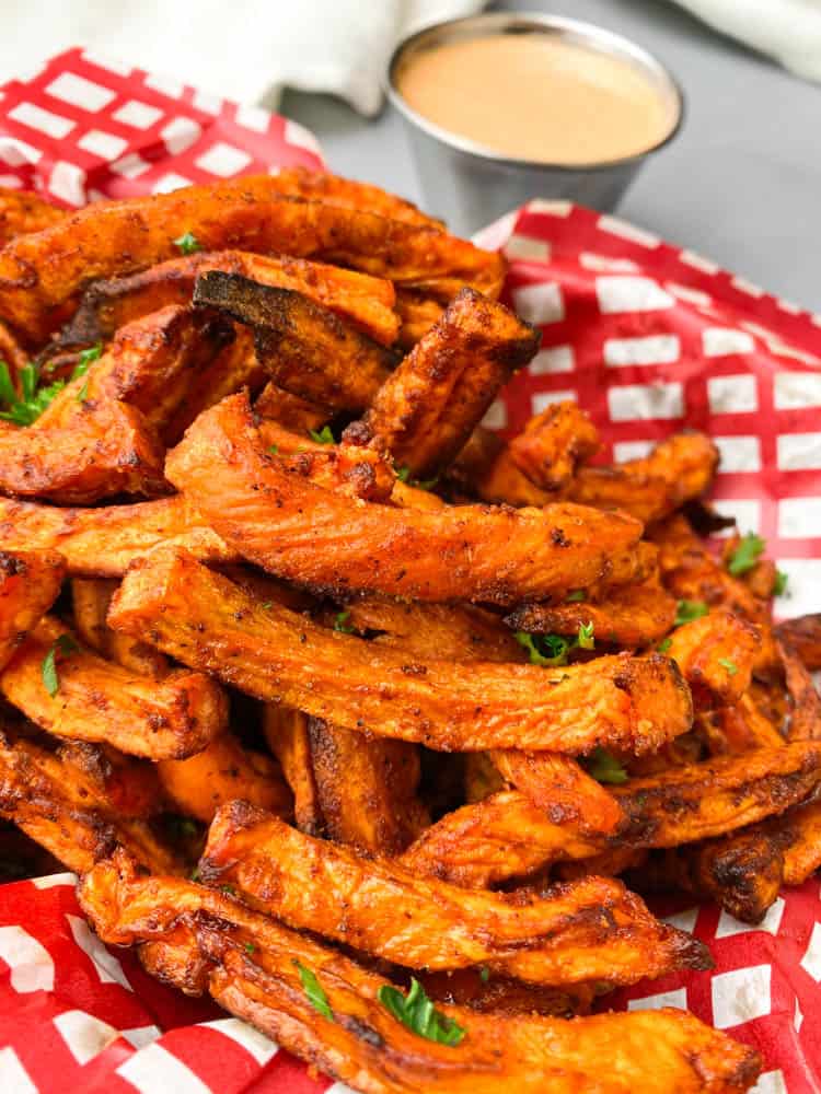 air fryer sweet potato fries in a basket with a red and white napkin