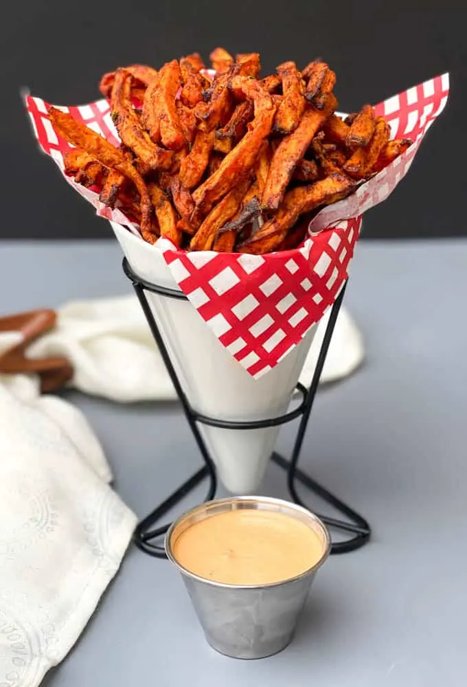 air fryer sweet potato fries in a white basket with a red and white napkin