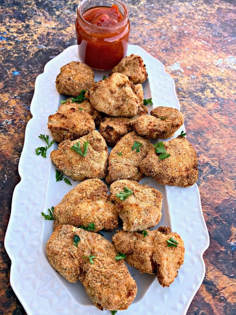 air fryer chicken nuggets on a white plate with ketchup