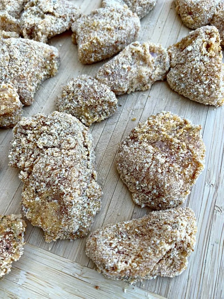 raw chicken nuggets with breading on a cutting board