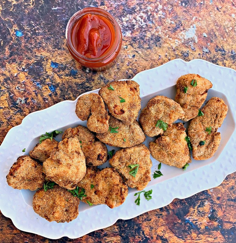 air fryer chicken nuggets on a white plate with ketchup