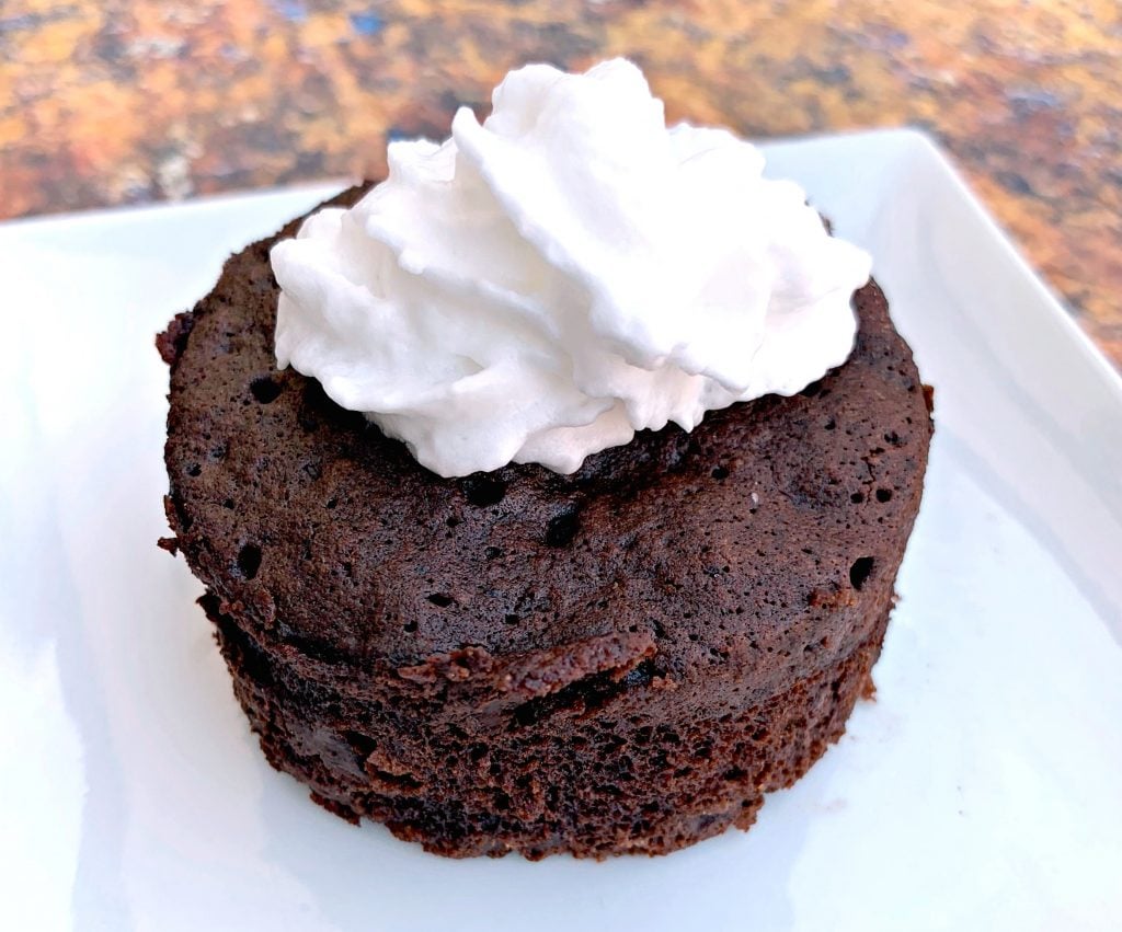 keto chocolate mug cake with whipped cream on a white plate