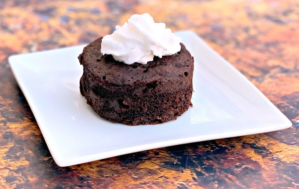 keto chocolate mug cake with whipped cream on a white plate