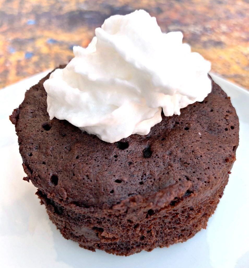 keto chocolate mug cake with whipped cream on a white plate