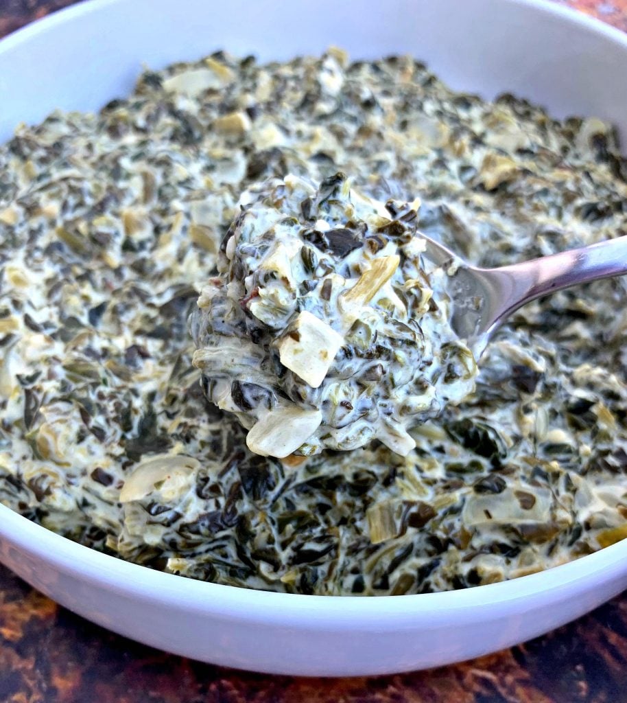 a spoonful of keto low carb creamed spinach in a white bowl