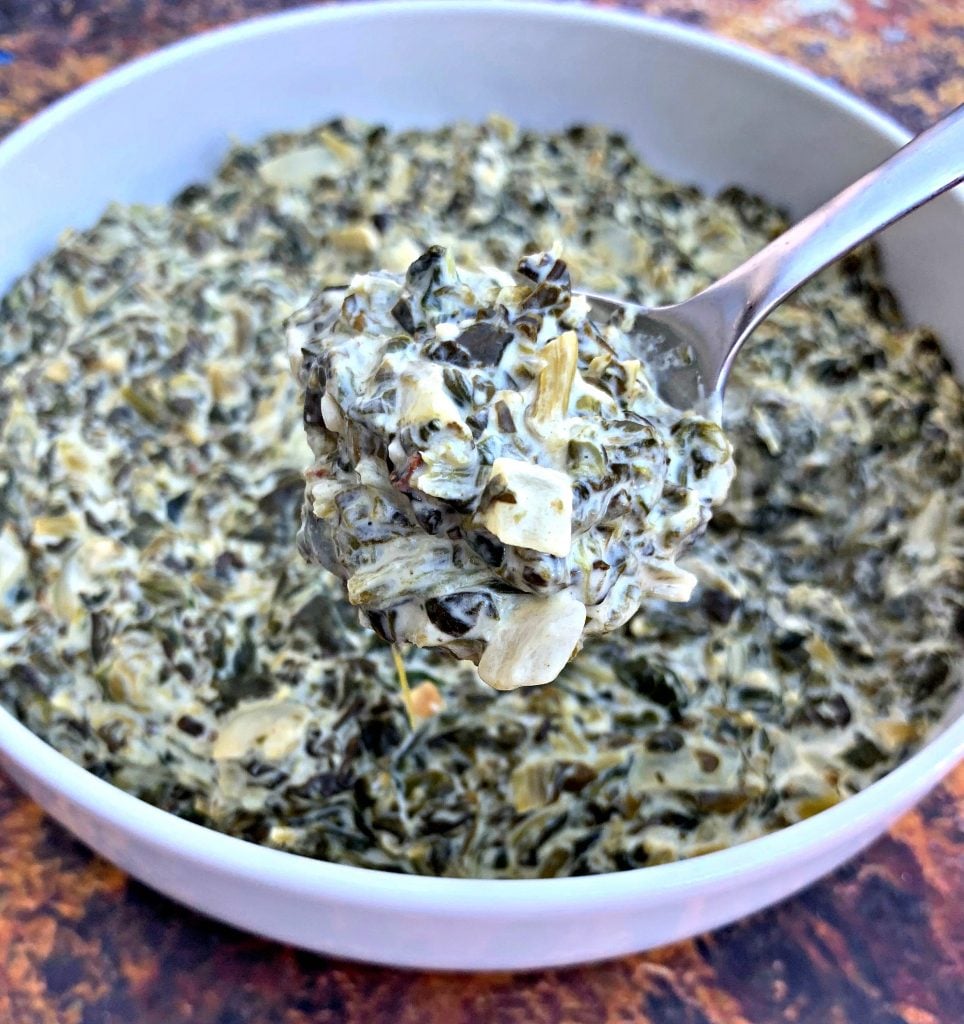 a spoonful of keto low carb creamed spinach in a white bowl