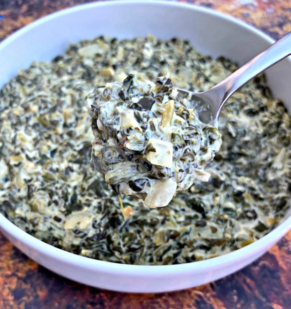 a spoonful of keto low carb creamed spinach in a white bowl