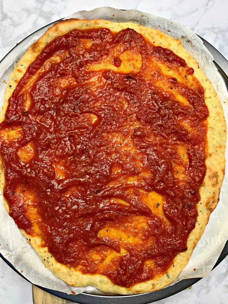 keto pepperoni pizza rolled out dough on a pizza pan with marinara