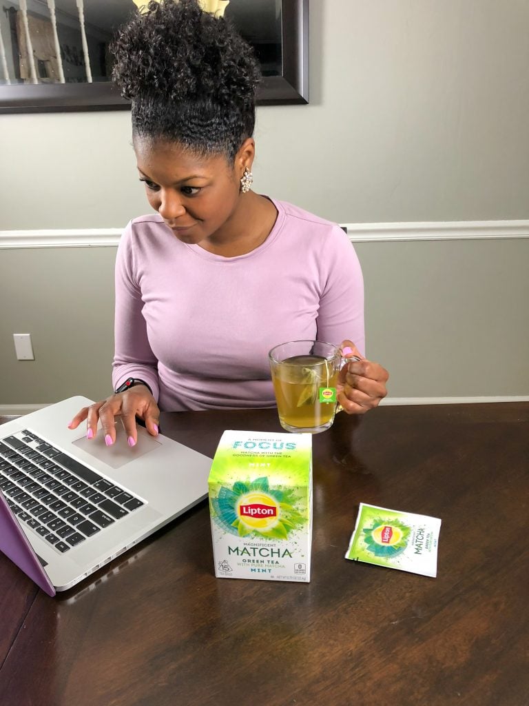 person working with tea in front of a computer