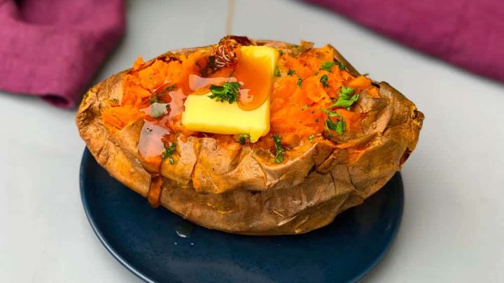 air fryer sweet potato with butter drizzled with honey on a blue plate