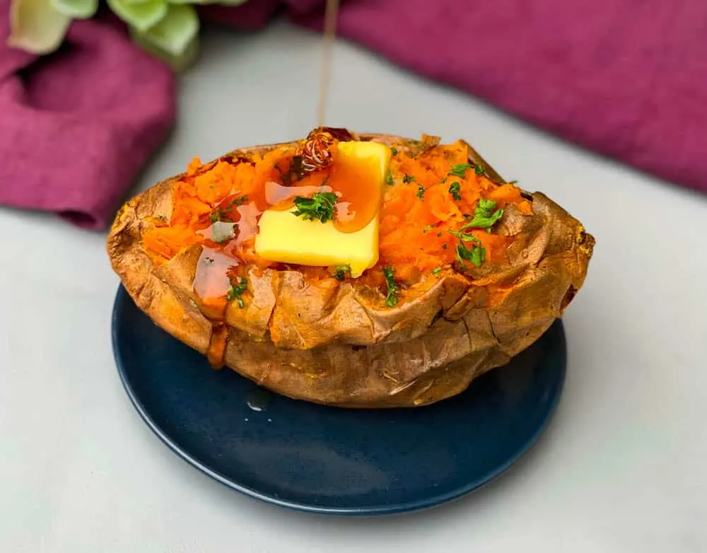 air fryer sweet potato with butter drizzled with honey on a blue plate