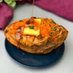 air fryer sweet potato with butter drizzled with honey on a blue plate