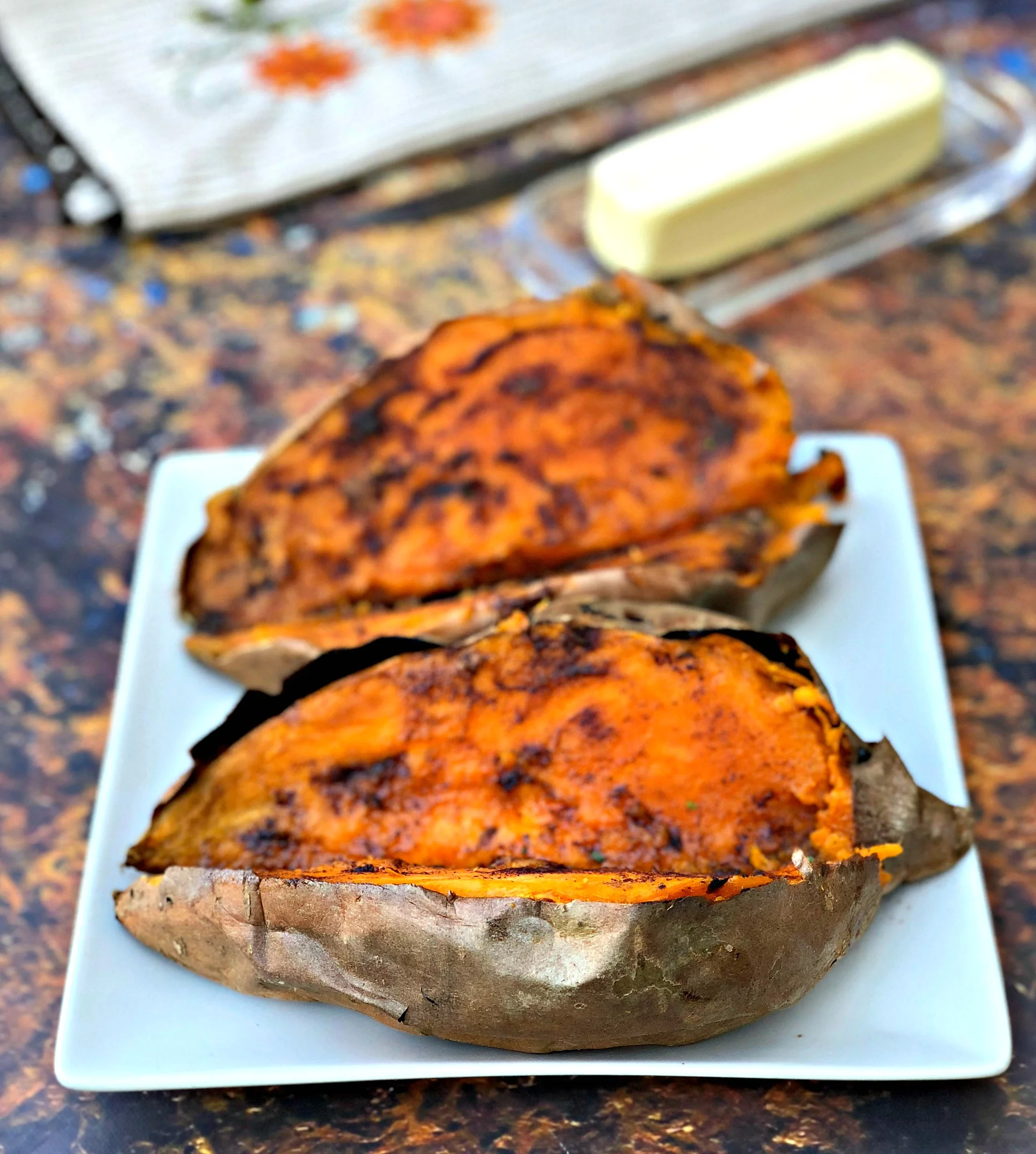 air fryer sweet potato with butter drizzled with honey on a blue plate