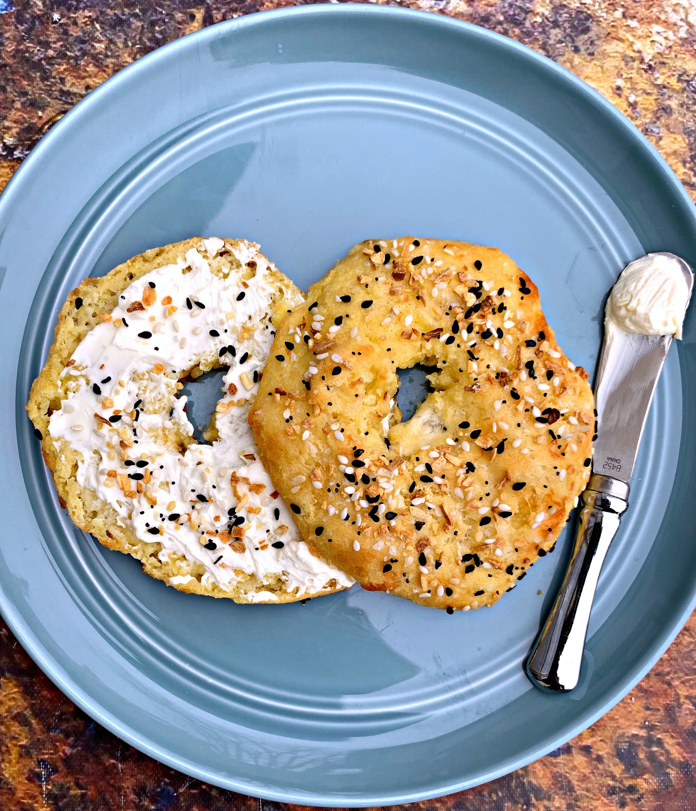 cooked keto fathead bagels on a blue plate with cream cheese