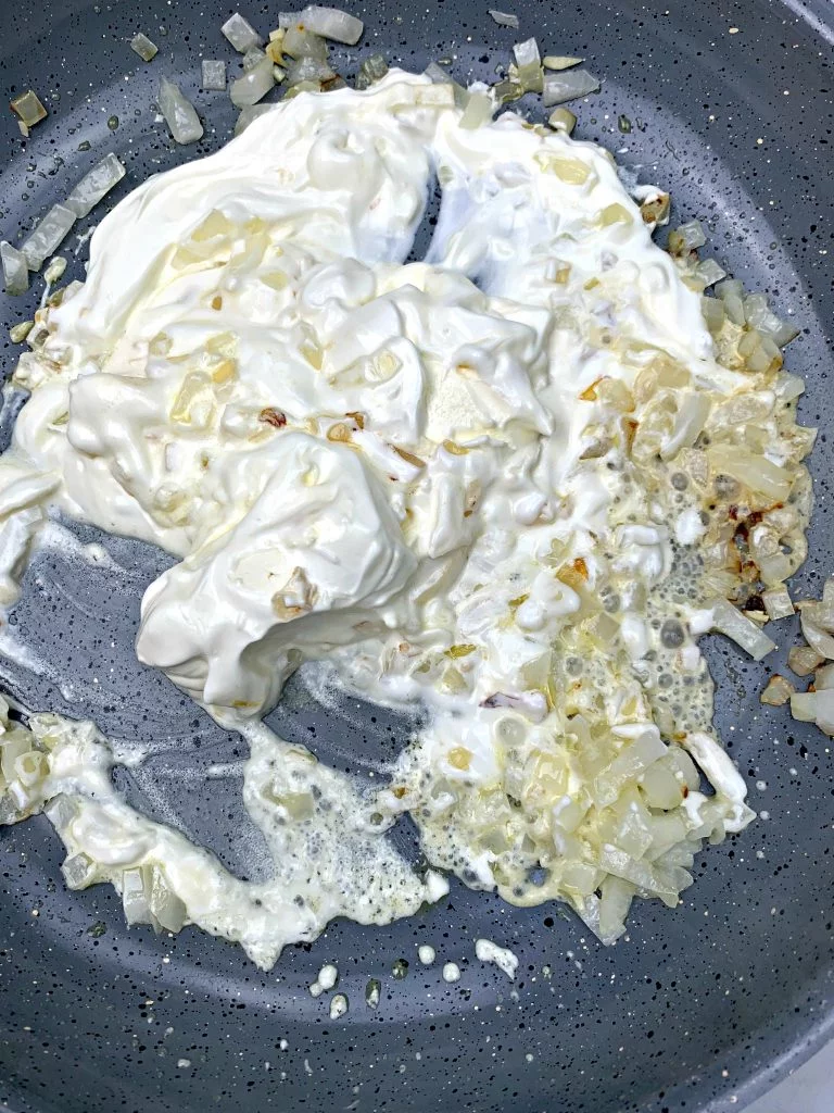 melted cream cheese with onions and garlic in a skillet