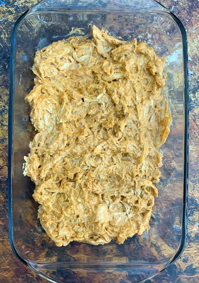 melted cheese and shredded chicken in a baking dish