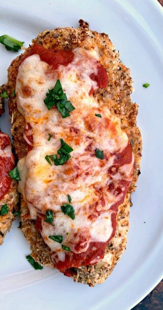 keto chicken parmesan with cauliflower mash and green beans on a white plate