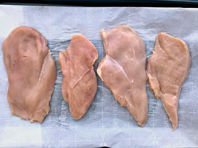 raw chicken breasts on parchment paper