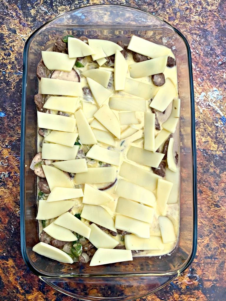 keto low carb philly cheesesteak in a glass pan with provolone cheese
