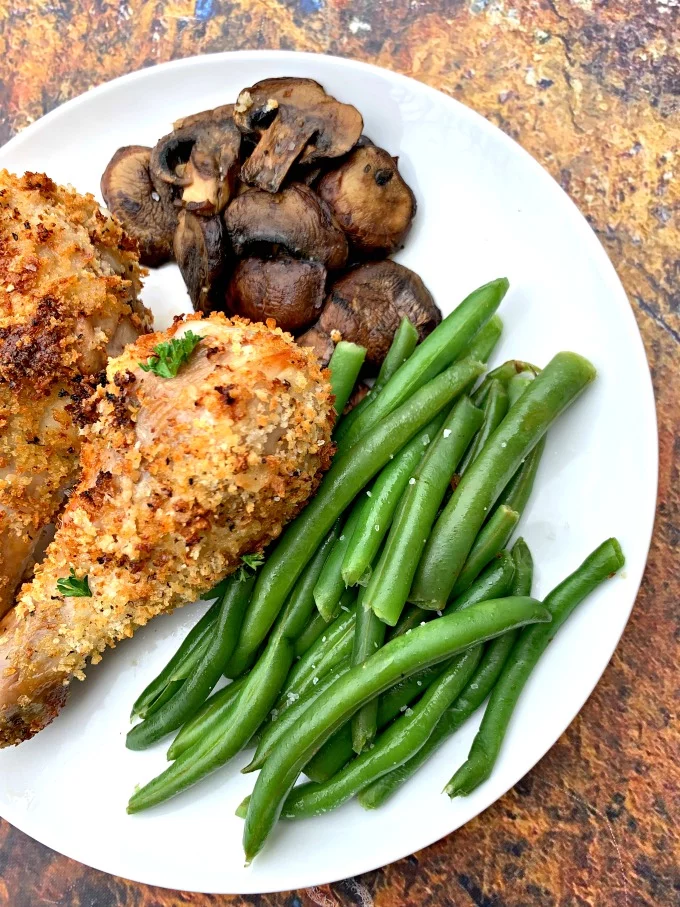 air fryer chicken drumsticks with green beans and mushrooms on a white plate