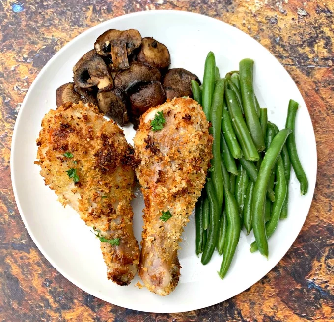 air fryer chicken drumsticks with green beans and mushrooms on a white plate