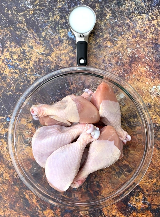 buttermilk and raw chicken drumsticks in a glass bowl