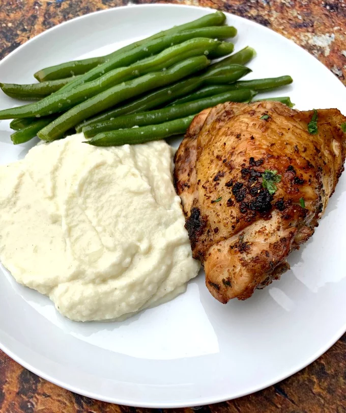 keto low carb air fryer cilantro lime chicken thighs in a white plate with cauliflower mash and green beans