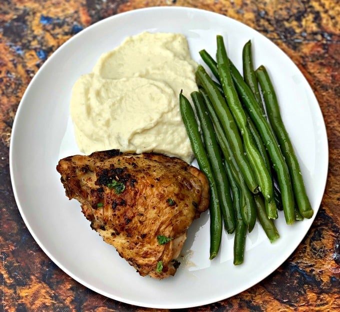 keto low carb air fryer cilantro lime chicken thighs in a white plate with cauliflower mash and green beans