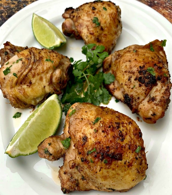 air fryer keto low carb cilantro lime chicken thighs on a white plate with lime and fresh cilantro
