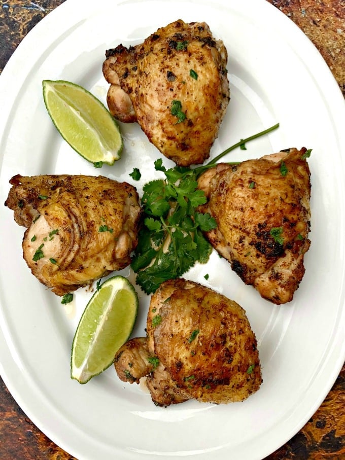 air fryer keto low carb cilantro lime chicken thighs on a white plate with lime and fresh cilantro