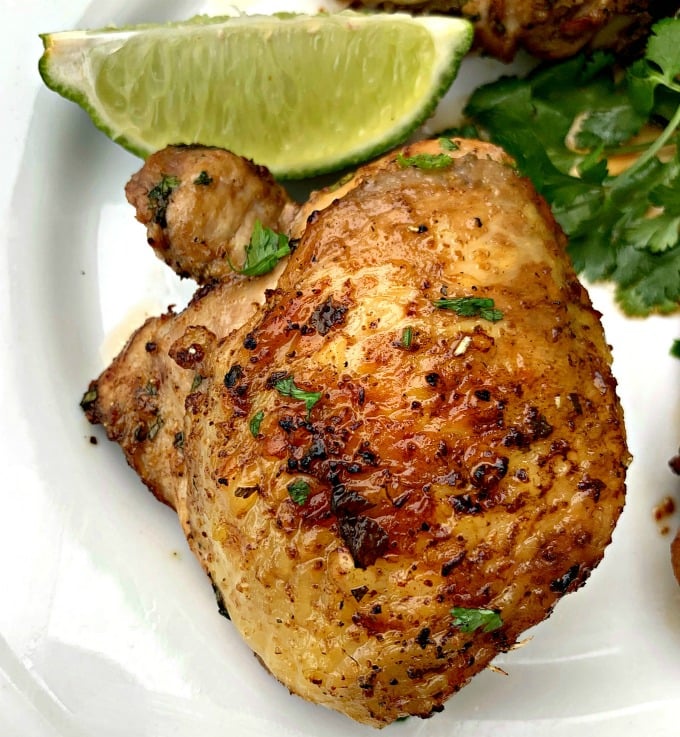 air fryer keto low carb cilantro lime chicken thighs on a white plate with lime and fresh cilantro