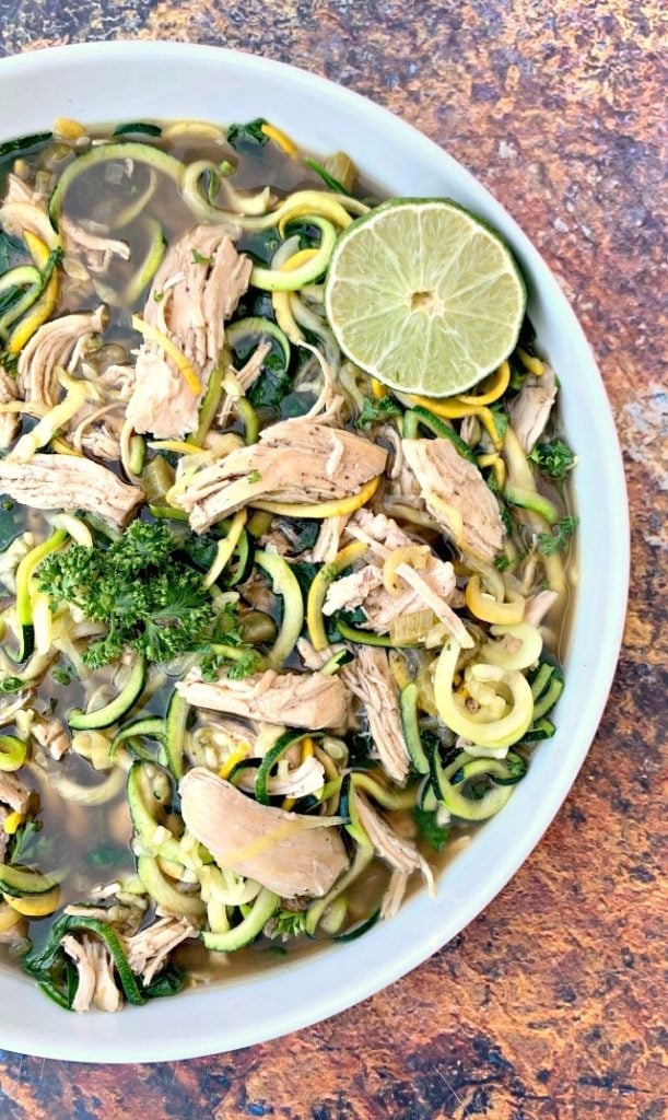 keto low carb chicken noodle soup with zucchini noodles in a white bowl