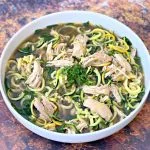 keto low carb chicken noodle soup with zucchini noodles in a white bowl