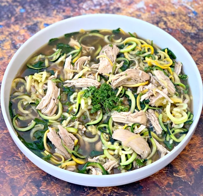 keto low carb chicken noodle soup with zucchini noodles in a white bowl