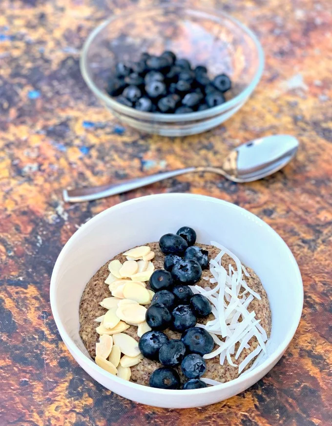 keto hemp oatmeal with blueberries, almonds, and coconut in a white bowl