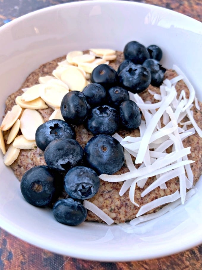 keto hemp oatmeal with blueberries, almonds, and coconut in a white bowl