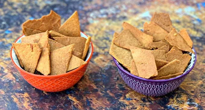 Keto Low-Carb Gluten-Free Homemade Tortilla Chips are a quick and easy recipe that uses a handful of ingredients. These crispy, crunchy chips are made with almond flour, Himalayan salt, and mozzarella and are practically no carb/carb free. You can also make crackers using the dough. The post also includes information on where to buy keto chips and what brands to look out for. #KetoRecipes #KetoTortillaChips