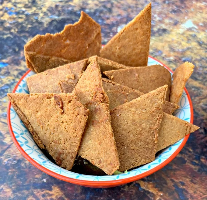 Keto Low-Carb Gluten-Free Homemade Tortilla Chips are a quick and easy recipe that uses a handful of ingredients. These crispy, crunchy chips are made with almond flour, Himalayan salt, and mozzarella and are practically no carb/carb free. You can also make crackers using the dough. The post also includes information on where to buy keto chips and what brands to look out for. #KetoRecipes #KetoTortillaChips