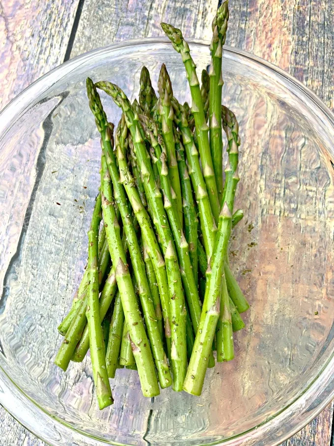 raw asparagus with olive oil in a glass bowl