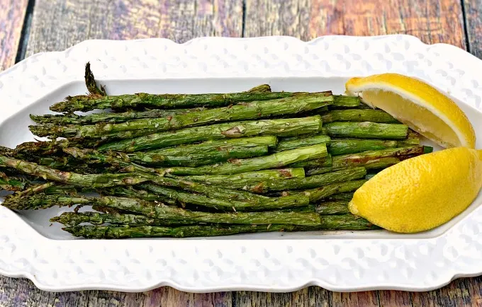 air fryer roasted asparagus on a white plate with lemon