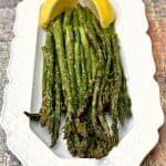 air fryer roasted asparagus on a white plate with lemon