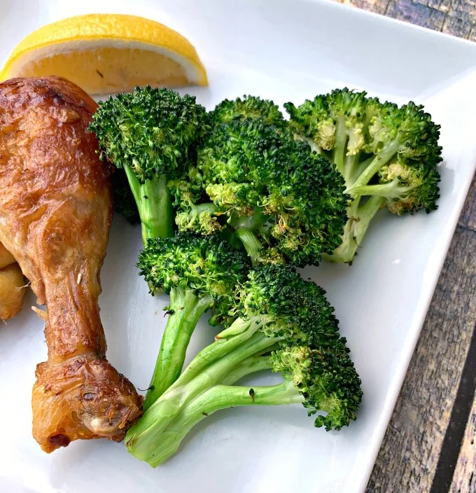 roasted air fryer broccoli with chicken on a white plate