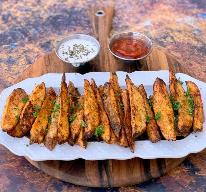 air fryer potato wedges on a white plate with ketchup and mayo