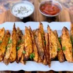 air fryer potato wedges on a white plate with ketchup and mayo