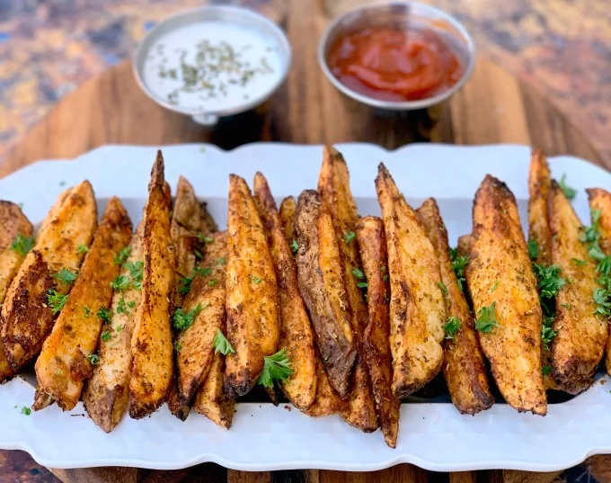 air fryer potato wedges on a white plate with ketchup and mayo