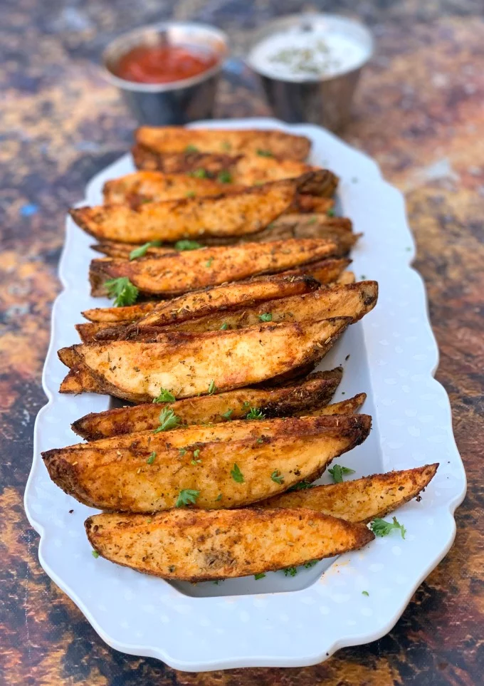 air fryer potato wedges on a white plate with ketchup and mayo