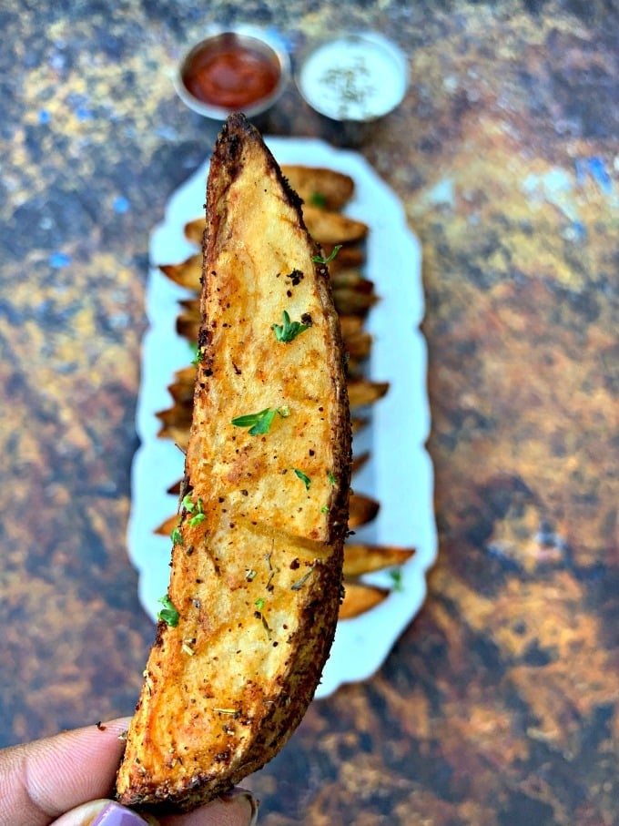 person holding air fryer potato wedge