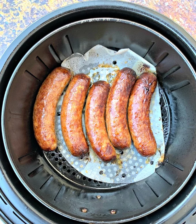raw air fryer sausage in an air fryer on parchment paper